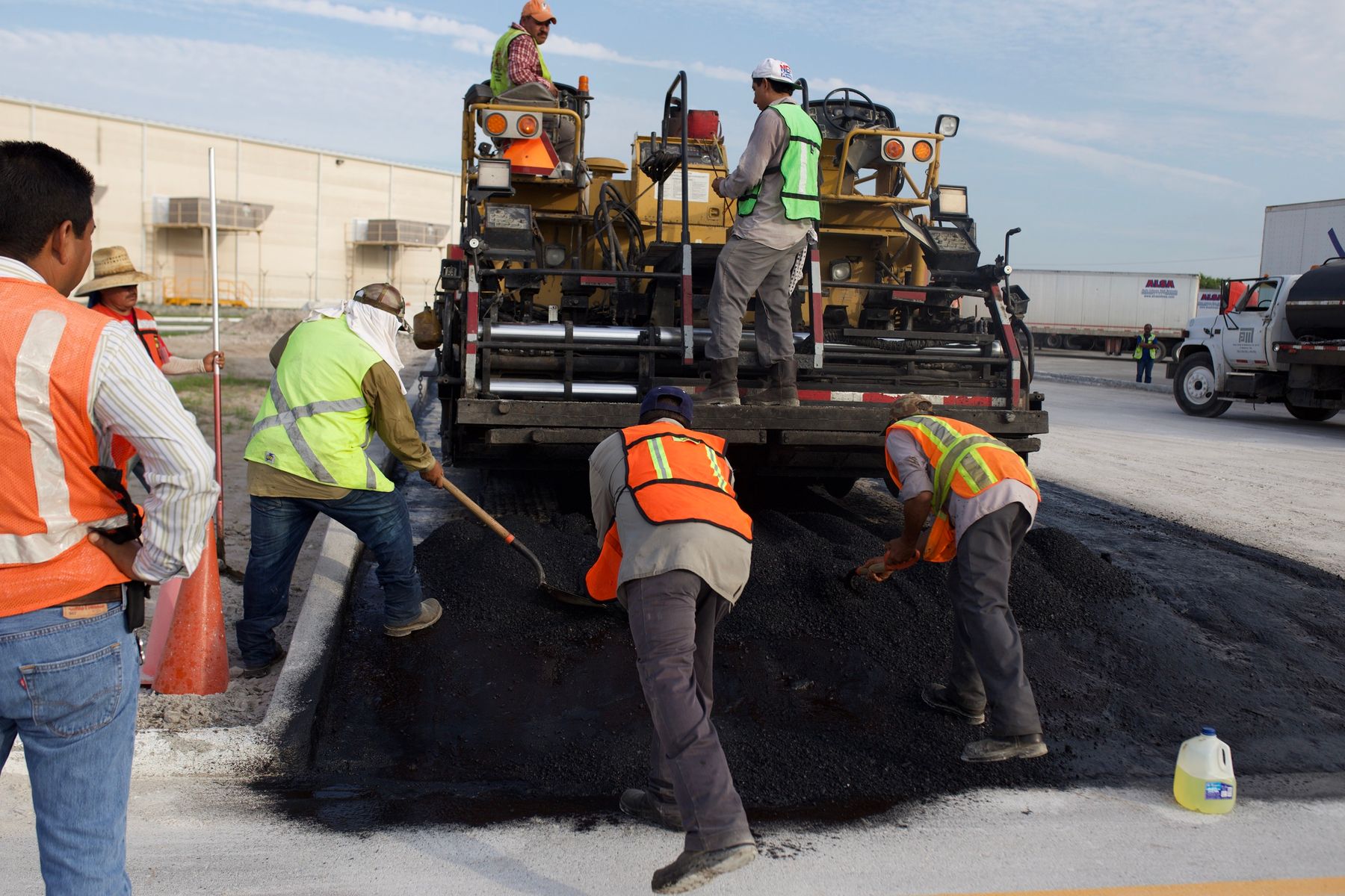 Road construction crew laying fresh asphalt with a paving machine