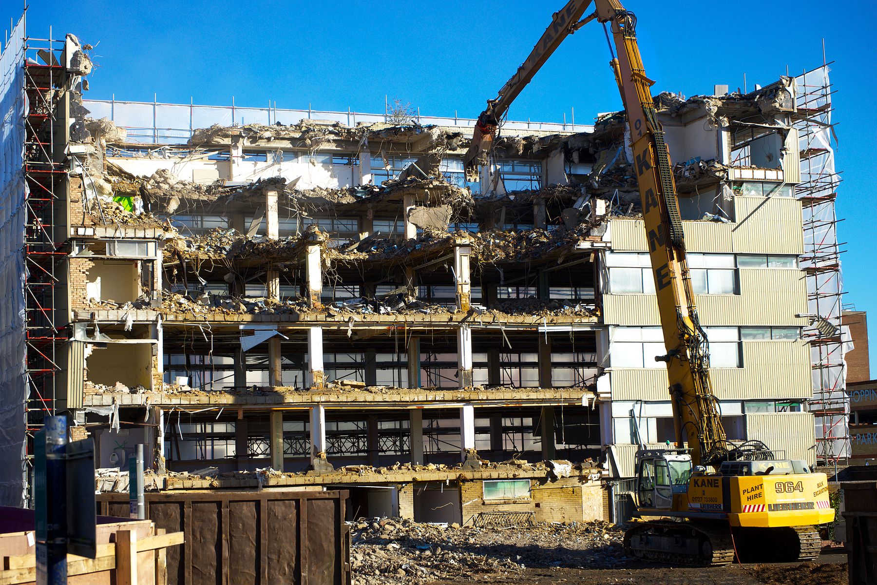 Excavator dismantling a multistory building at a demolition site