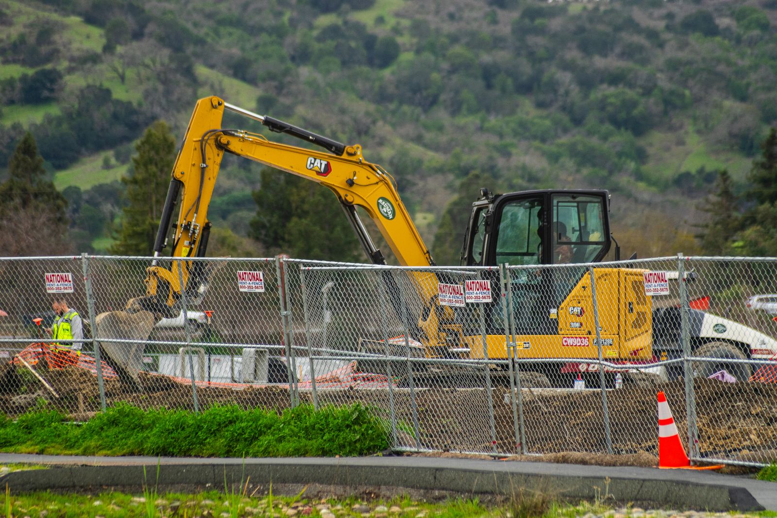 Excavator performing site work near a mountain landscape
