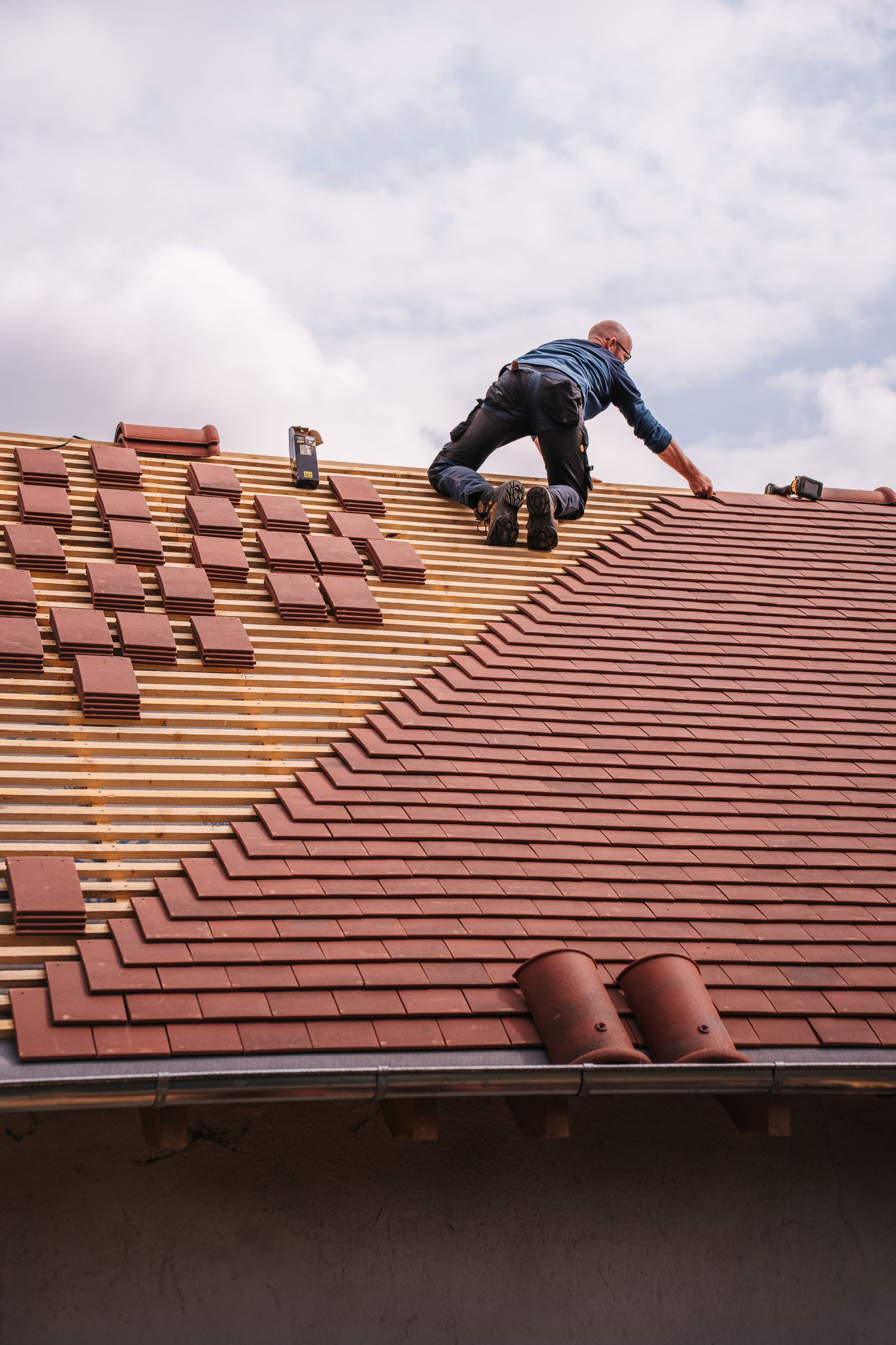 Roofer installing tile across a residential roof