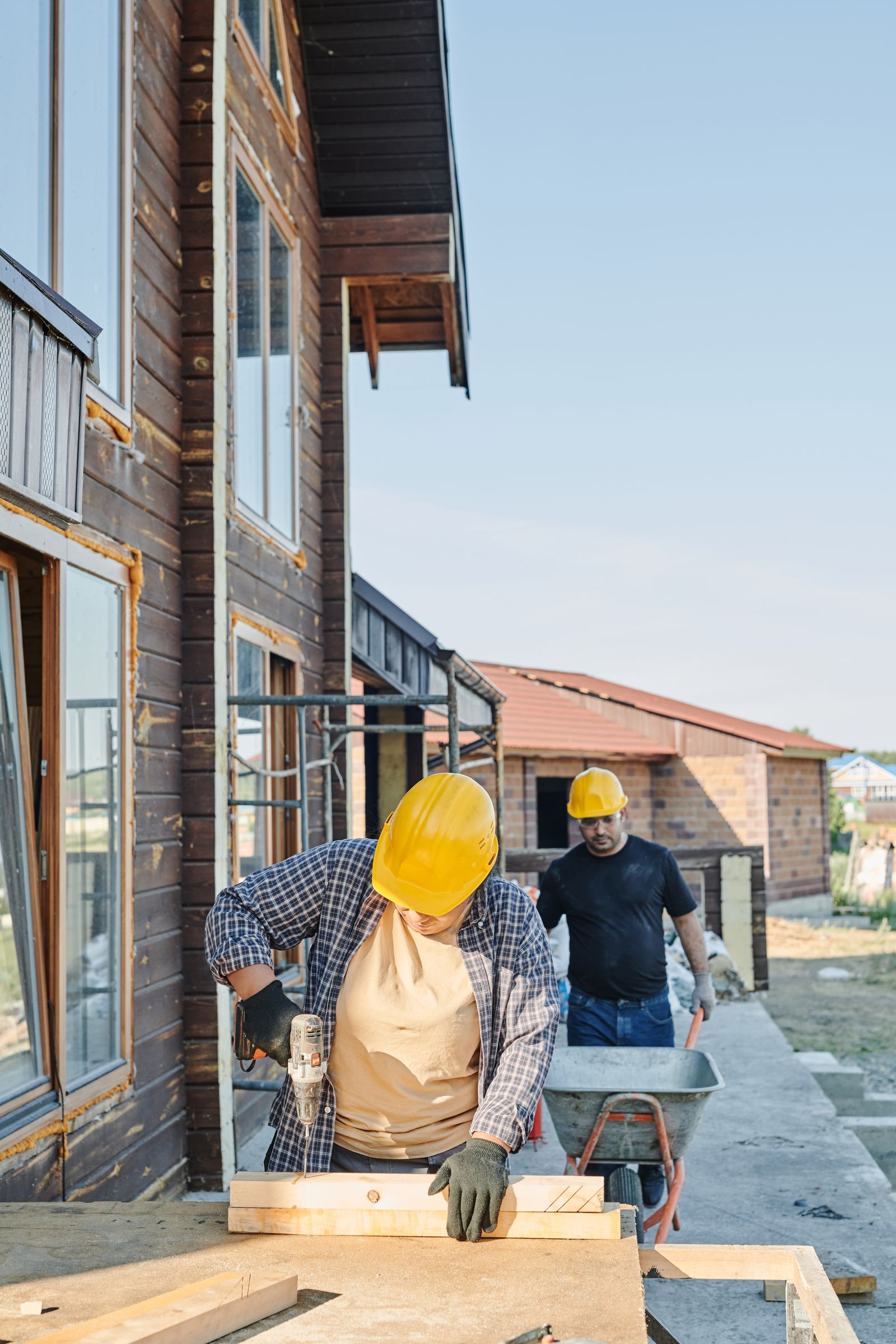 Carpenters cutting timber beside a house construction project