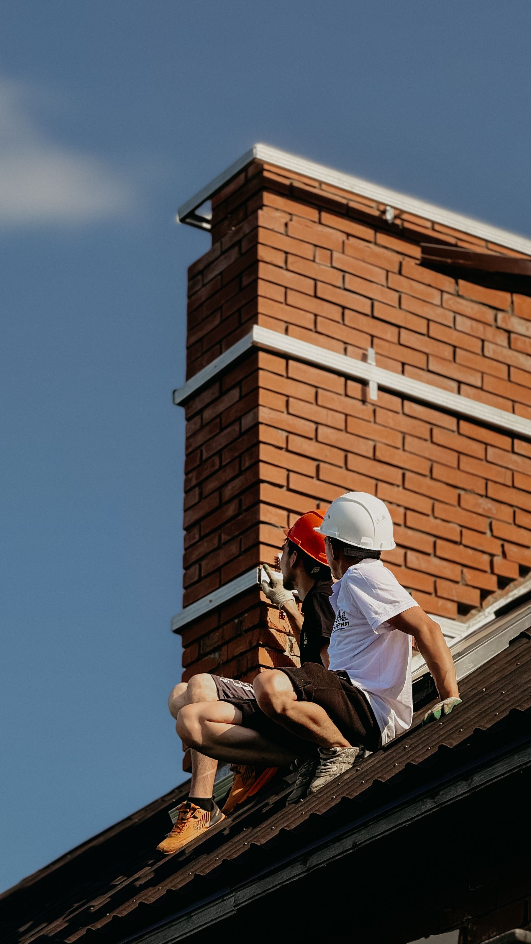 Construction crew repairing brickwork on a residential chimney