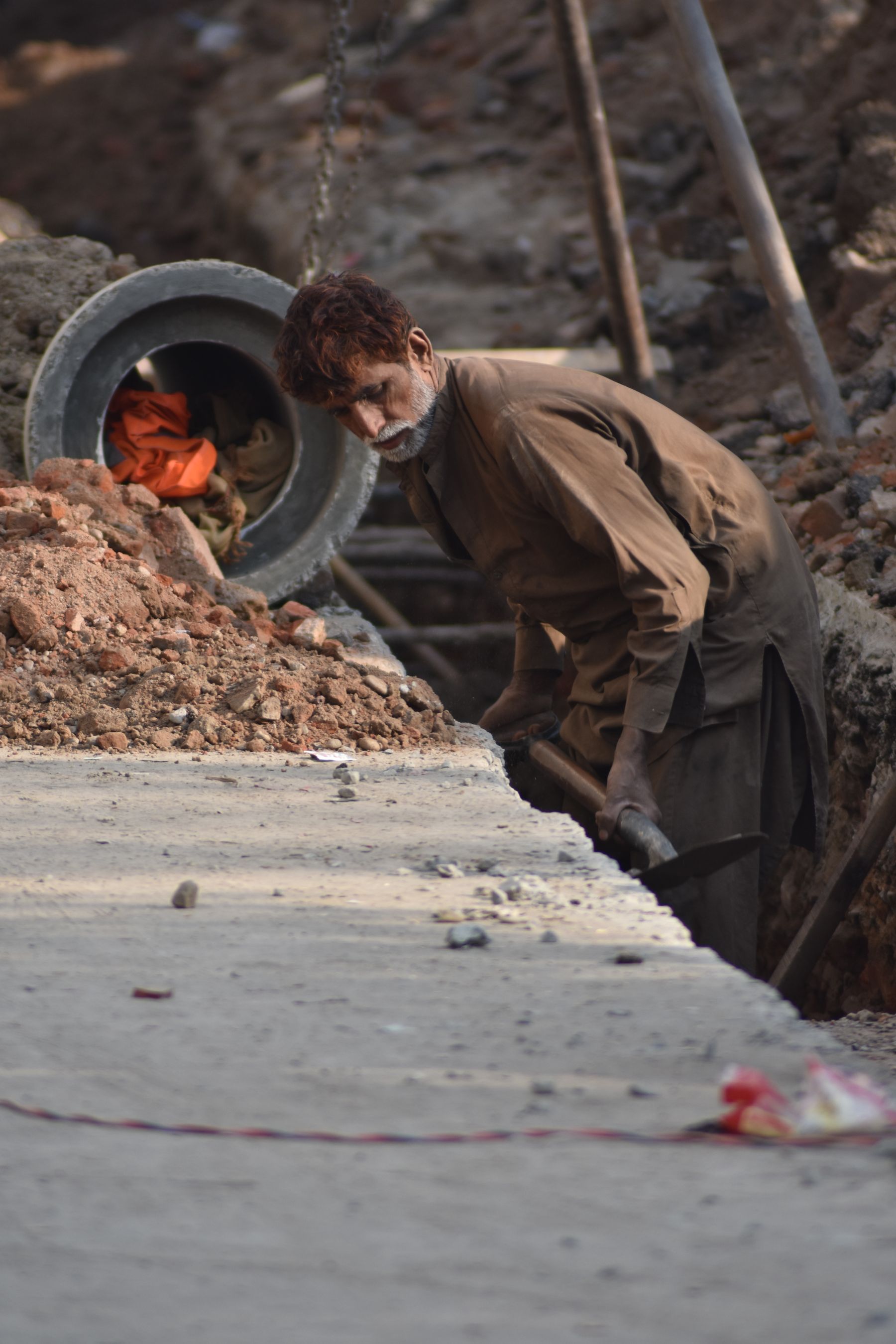 Worker installing drainage pipe in an excavated construction trench