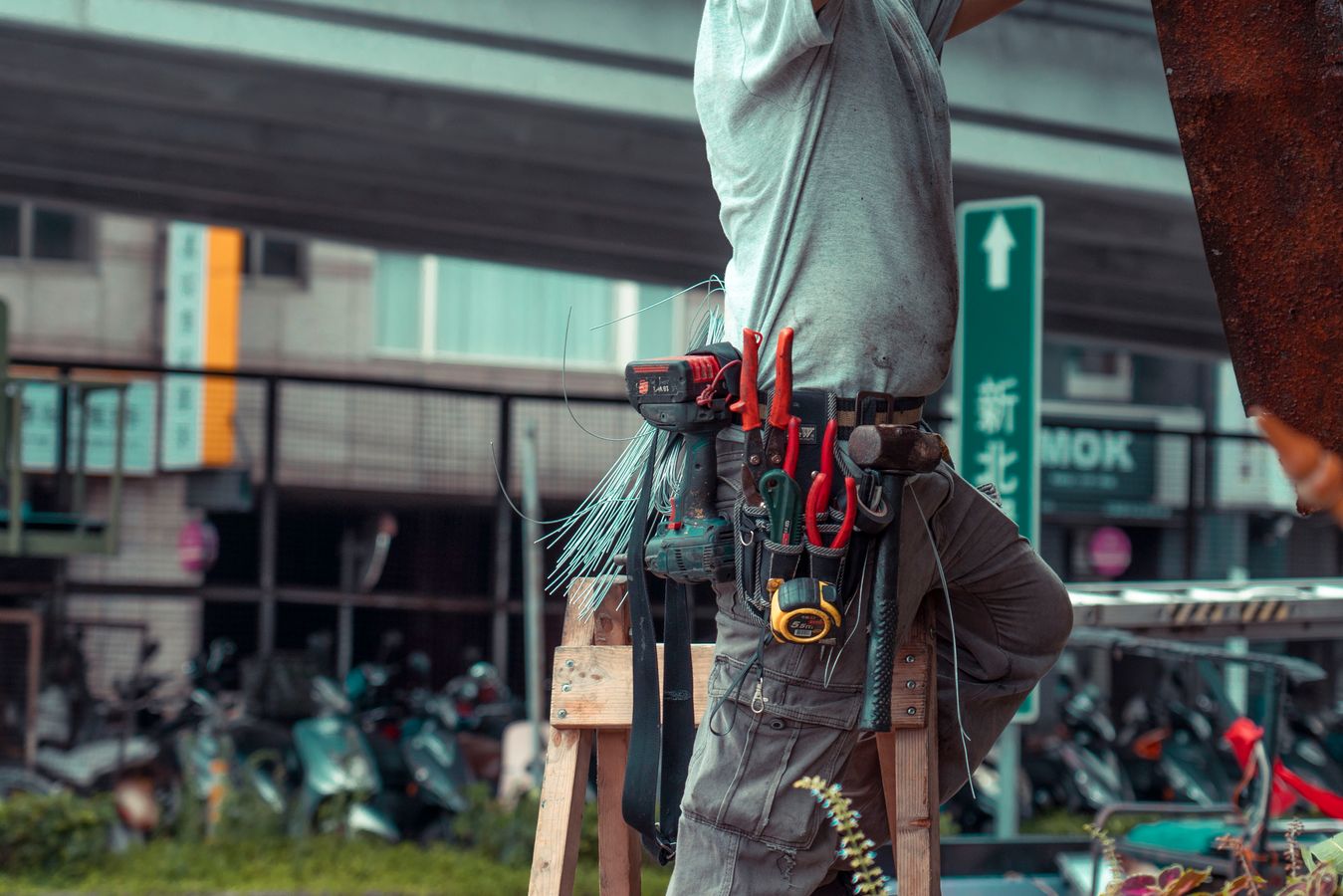 Professional handyman working from a ladder with a full tool belt