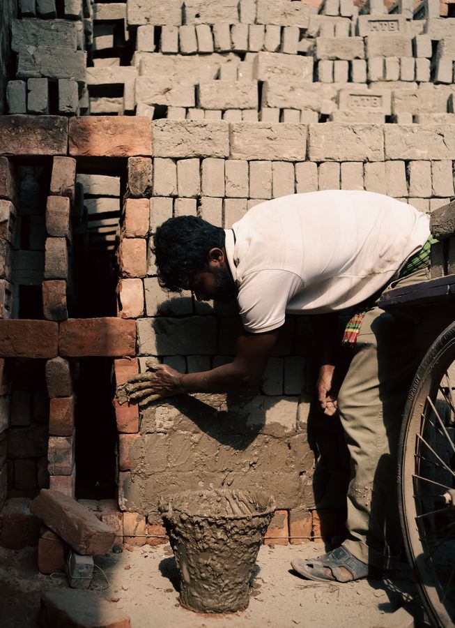 Masonry worker applying mortar while building a brick wall